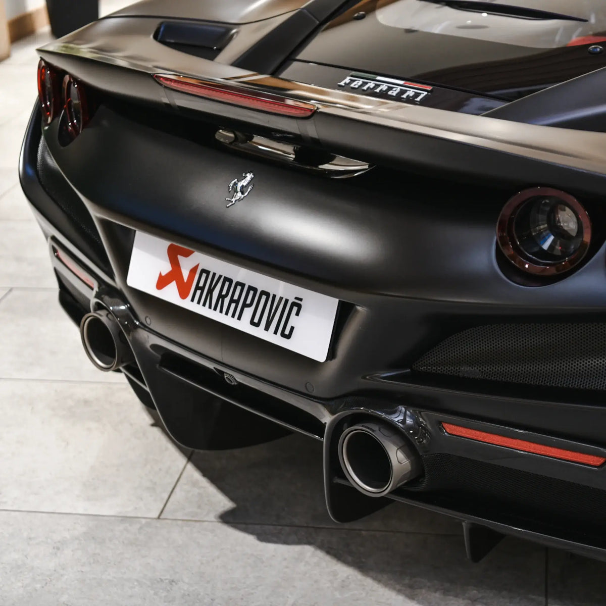 Close-up of the titanium tailpipes on a Ferrari F8 Tributo during a PERON Automotive event at The Motorist, showcasing the intricate design and aggressive styling.