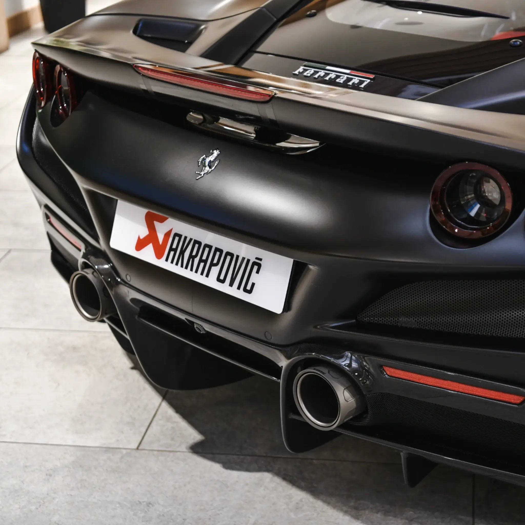 Close-up of the titanium tailpipes on a Ferrari F8 Tributo during a PERON Automotive event at The Motorist, showcasing the intricate design and aggressive styling.