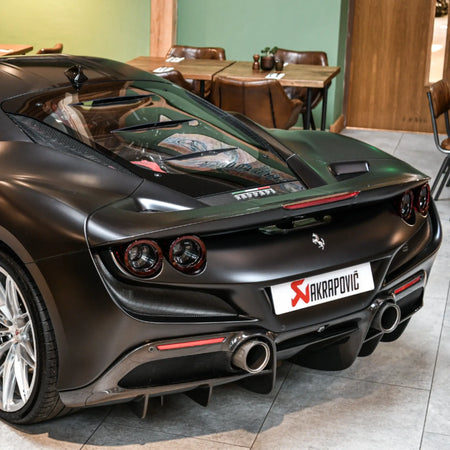 Ferrari F8 Tributo parked at The Motorist during a PERON Automotive event, highlighting the rear angle fitted with the Evolution Line performance exhaust.