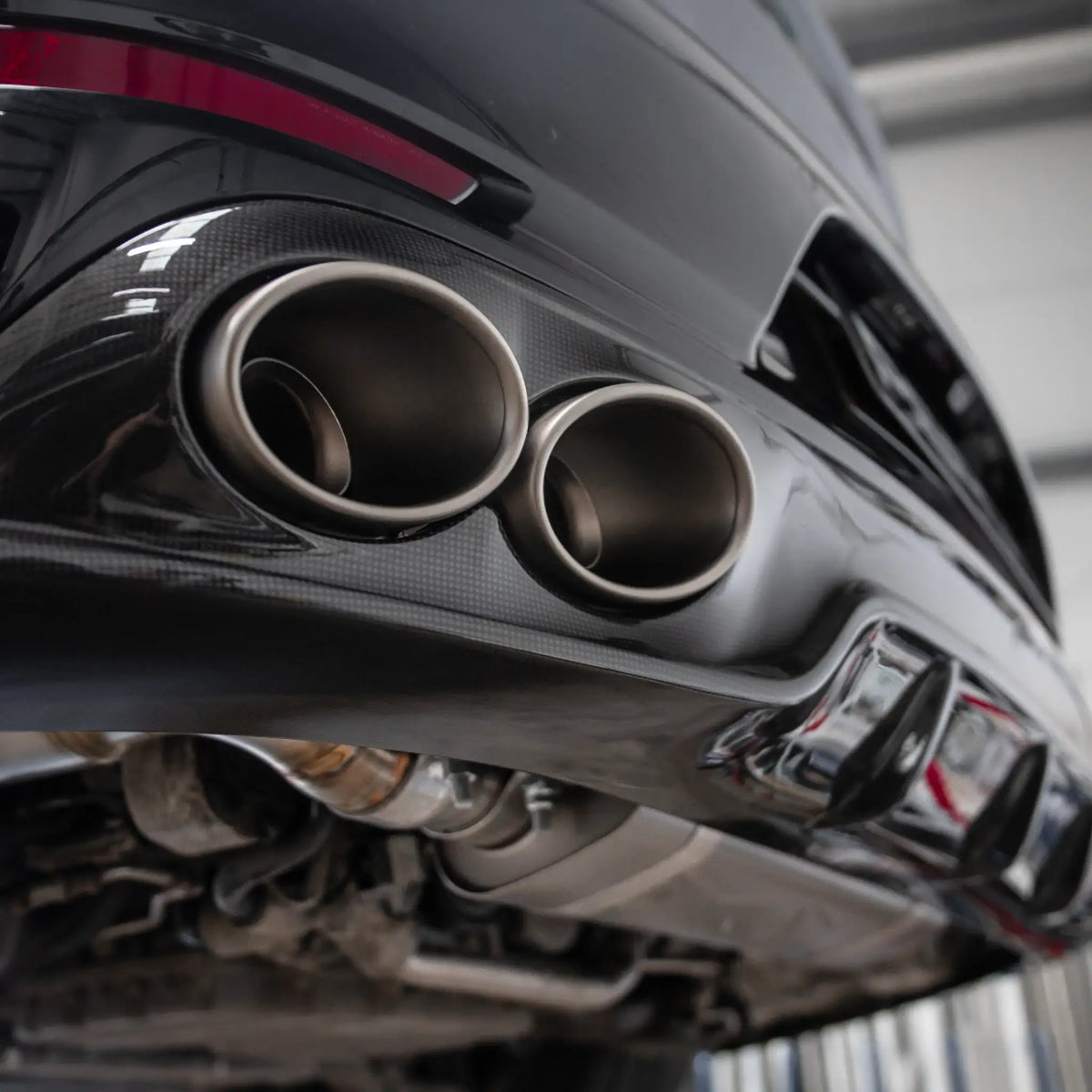 Low-angle shot of the Porsche 911 Turbo S 991.2, highlighting the Akrapovic titanium tailpipes and carbon diffuser installed at PERON Performance.