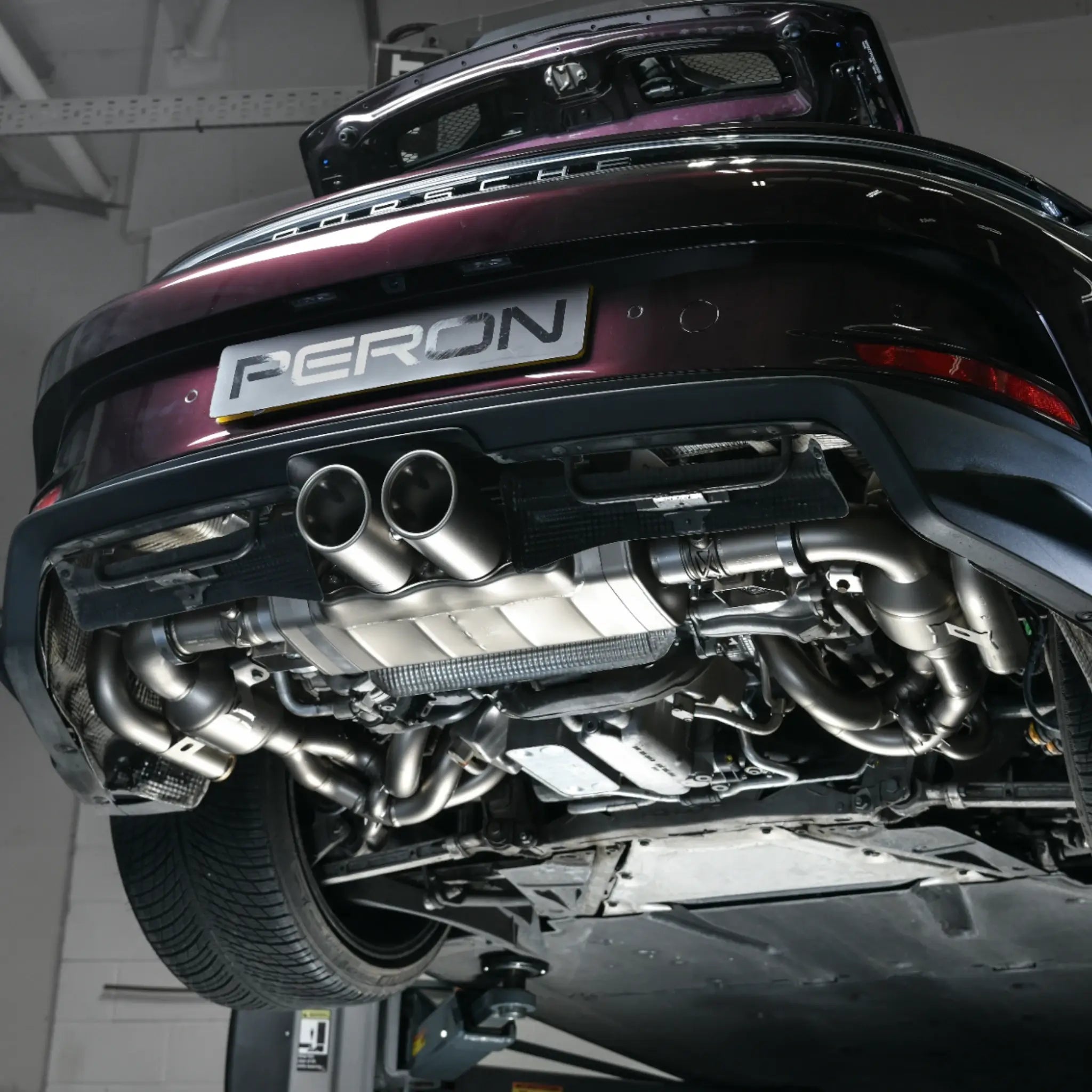 Underneath view of Porsche 911 GT3 Touring (992) with Akrapovič Slip-On Race Line Titanium Performance Exhaust installed at PERON Automotive, highlighting sleek design and seamless fitment.