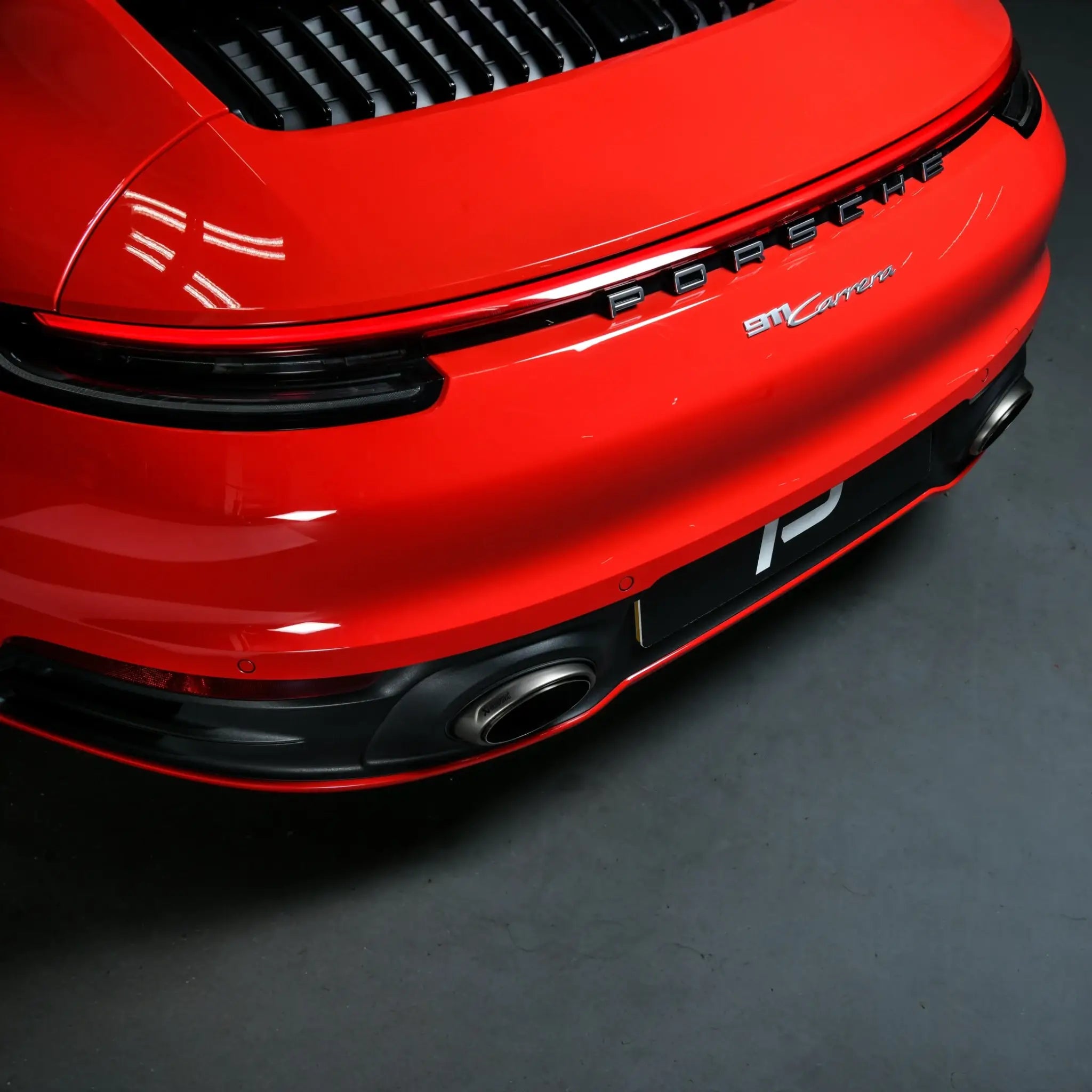 Rear bumper shot highlighting seamless fitment and integration of Akrapovic Slip-On Race Line with Porsche 911 Carrera 992 design lines.