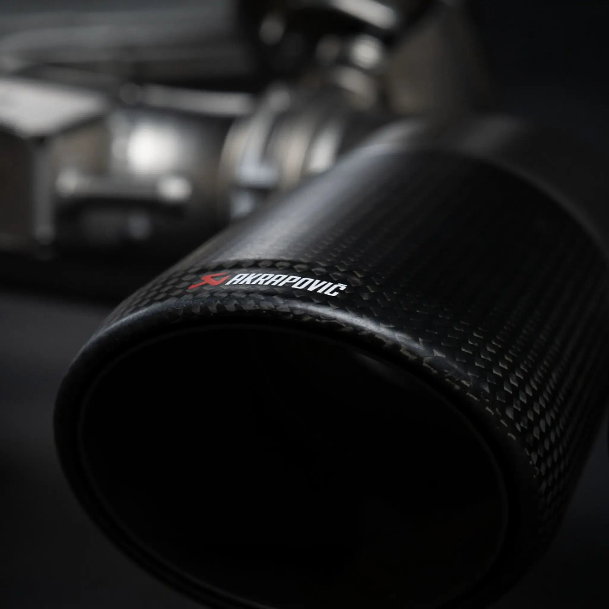 Detailed close-up of the Akrapovic carbon tailpipe, capturing the premium finish of the Evolution Line titanium performance exhaust system on the Porsche Cayenne 536.2.