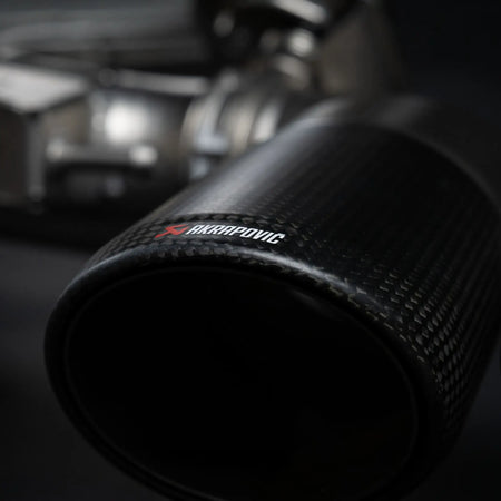 Detailed close-up of the Akrapovic carbon tailpipe, capturing the premium finish of the Evolution Line titanium performance exhaust system on the Porsche Cayenne 536.2.