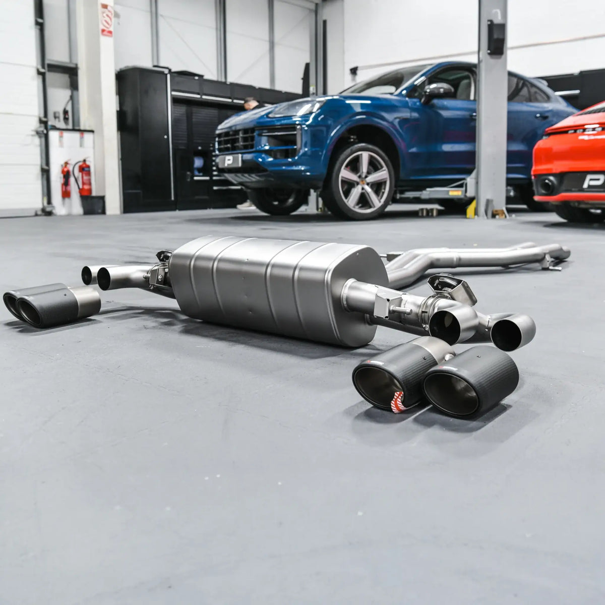 Akrapovic Evolution Line titanium performance exhaust system laid out with Porsche Cayenne 536.2 in the background.