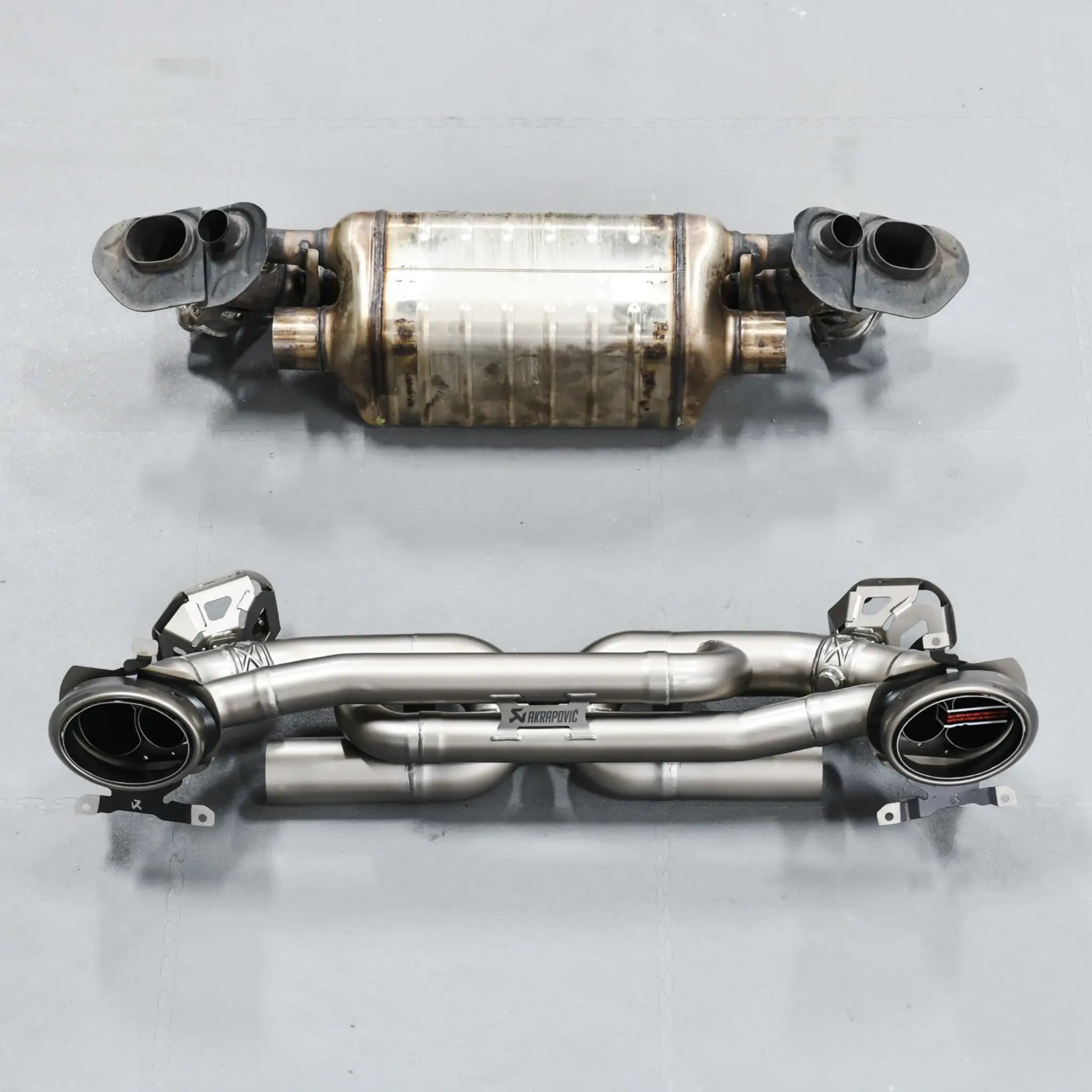 Side-by-side comparison of stock exhaust and Akrapovic Slip-On Race Line, showcasing size and build quality differences.