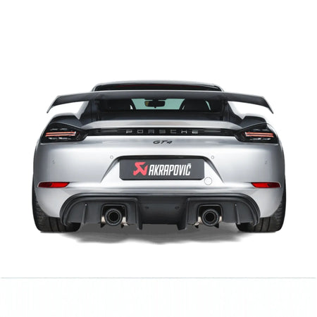 Straight rear view of Porsche 718 Cayman GT4 fitted with the Akrapovič Slip-On Race Line (Titanium), emphasising the sleek titanium tailpipes and precision fitment.