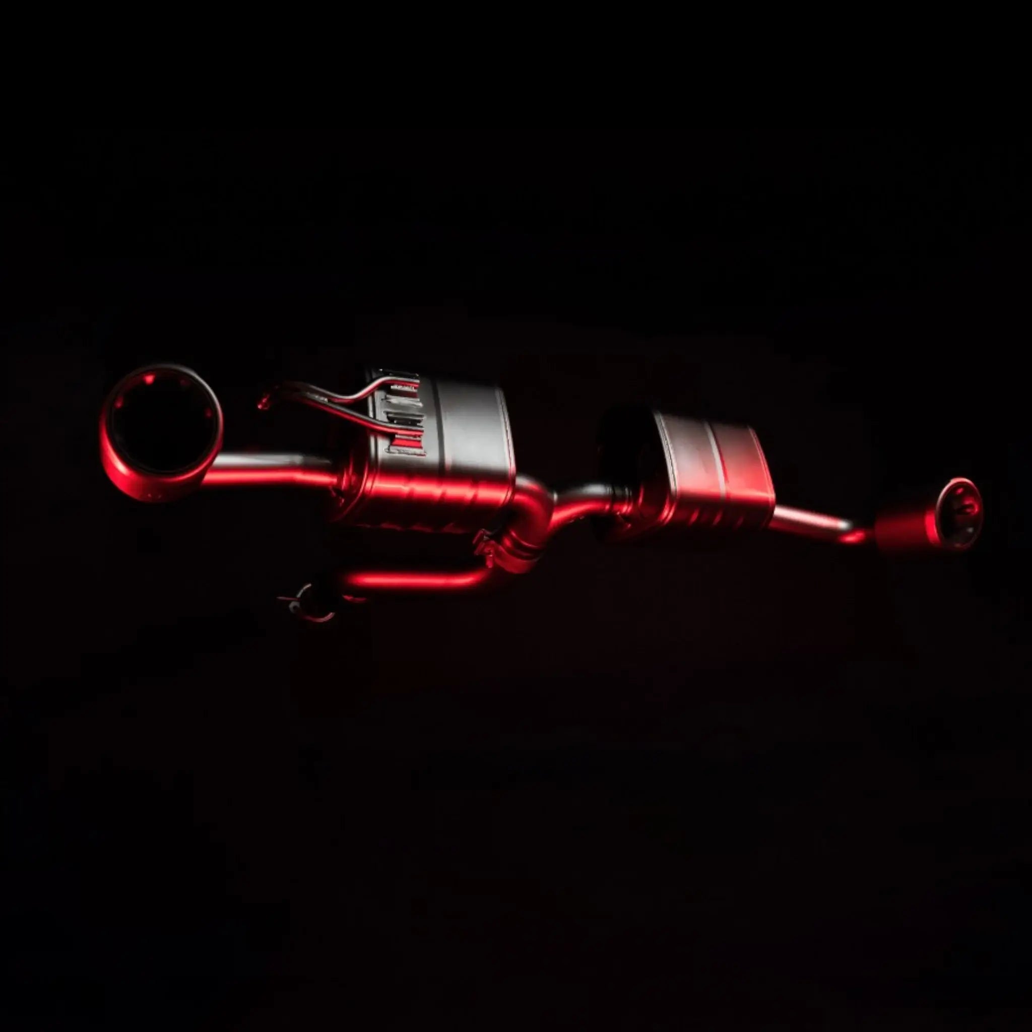 Artistic shot of the Akrapovič Slip-On Race Line (Titanium) system for the Toyota GR Yaris (Gen 2), illuminated with red accent lighting to emphasise its advanced design.