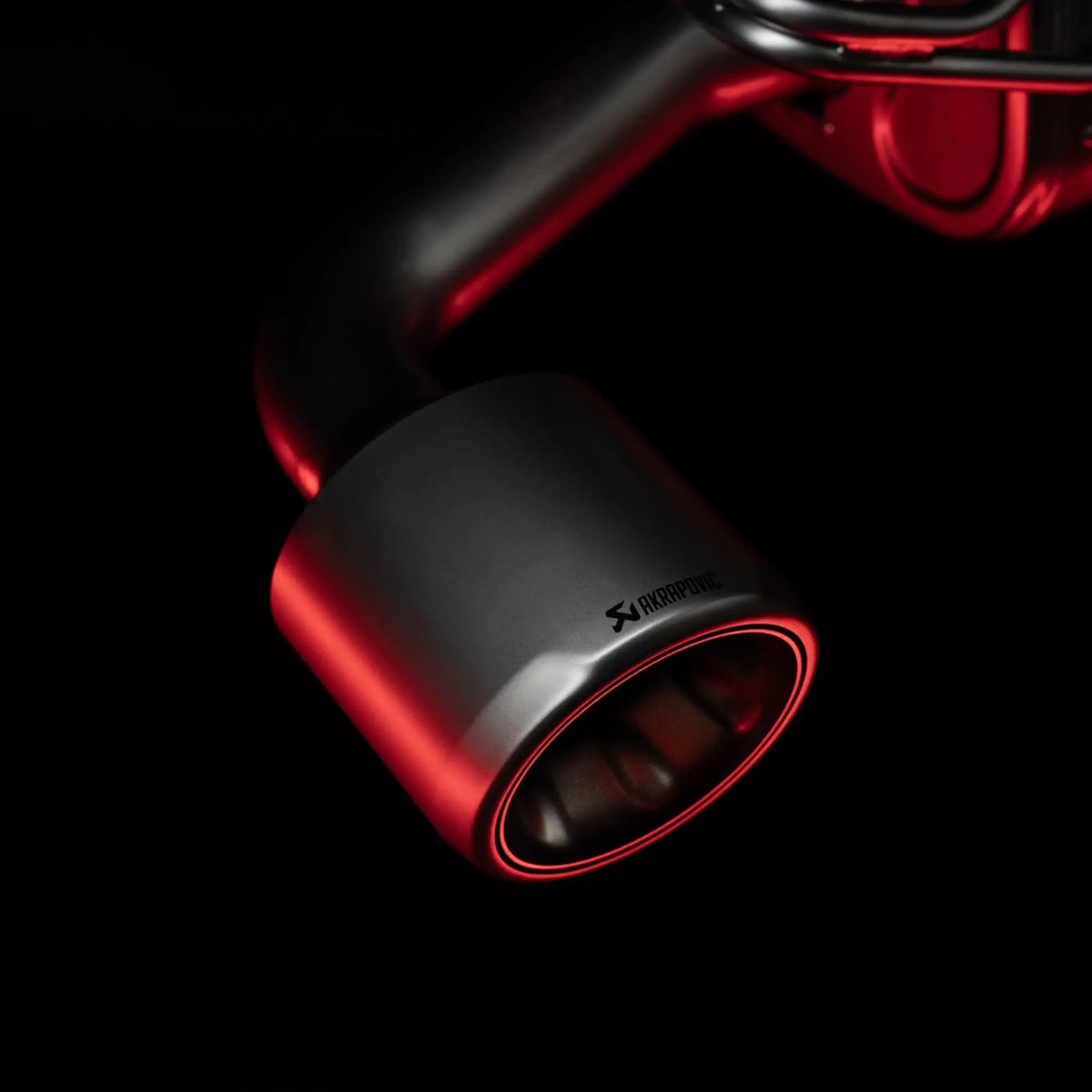 Close-up of the titanium tailpipe from the Akrapovič Slip-On Race Line (Titanium) on the Toyota GR Yaris (Gen 2), with red accent lighting highlighting its premium finish.